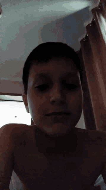 a young boy without a shirt is taking a selfie