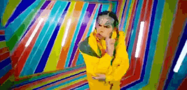 a man in a yellow jacket is standing in front of a colorful wall in a room .