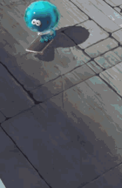 a blue ball is sitting on a skateboard on a tiled floor