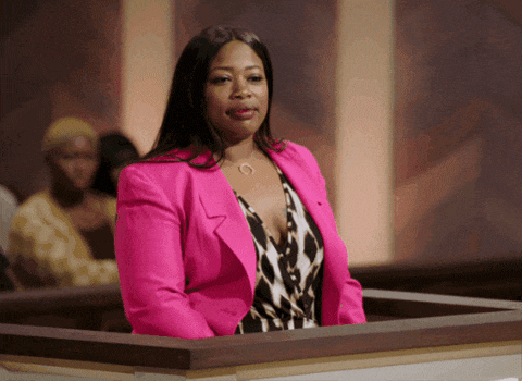 a woman in a bright pink jacket stands at a podium