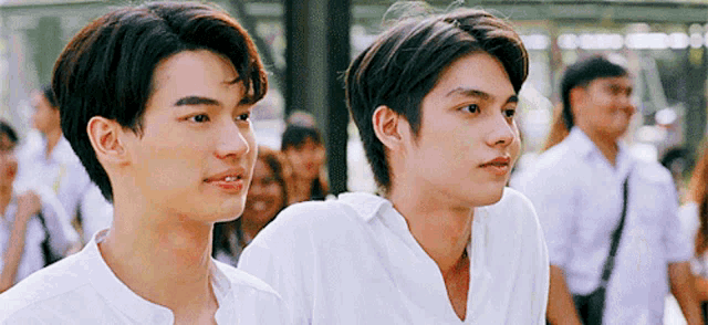 two young men in white shirts are standing next to each other .
