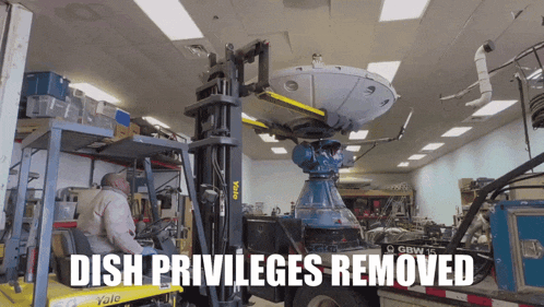 a man in a yale forklift is moving a dish satellite
