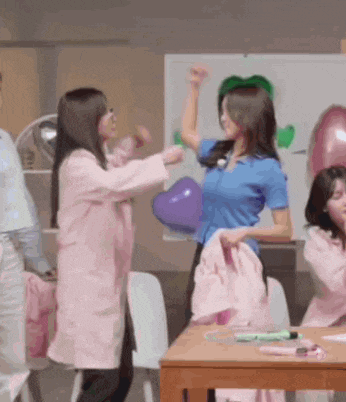 a group of women are standing around a table playing with balloons