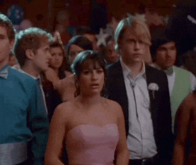 a woman in a pink strapless dress is standing in a crowd of people at a prom .