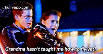 a boy and a girl are sitting on a roller coaster and the girl is crying .