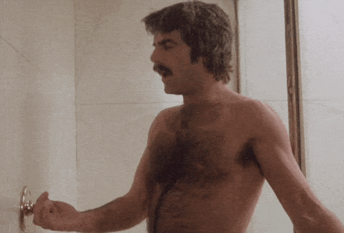 a man with a mustache is taking a shower without a shirt
