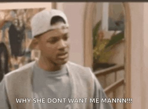 a man wearing a baseball cap is talking to a woman in a living room .
