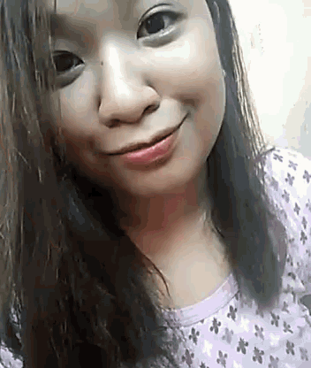 a close up of a woman 's face with a purple shirt on and a smile on her face .
