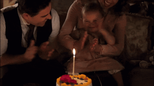 a baby is sitting in front of a birthday cake with a candle