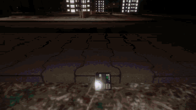 a remote control sits on a brick sidewalk in front of a building at night