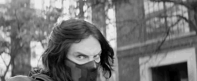 a black and white photo of a man wearing a mask and a backpack .