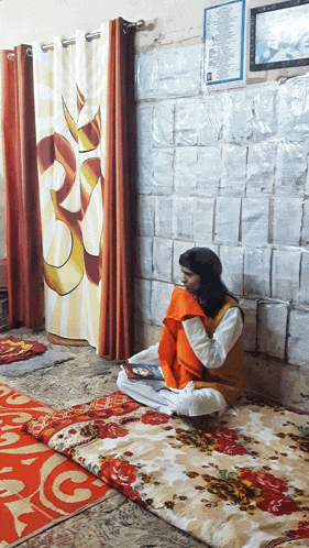 a woman sits on a blanket in front of a curtain with a om symbol on it