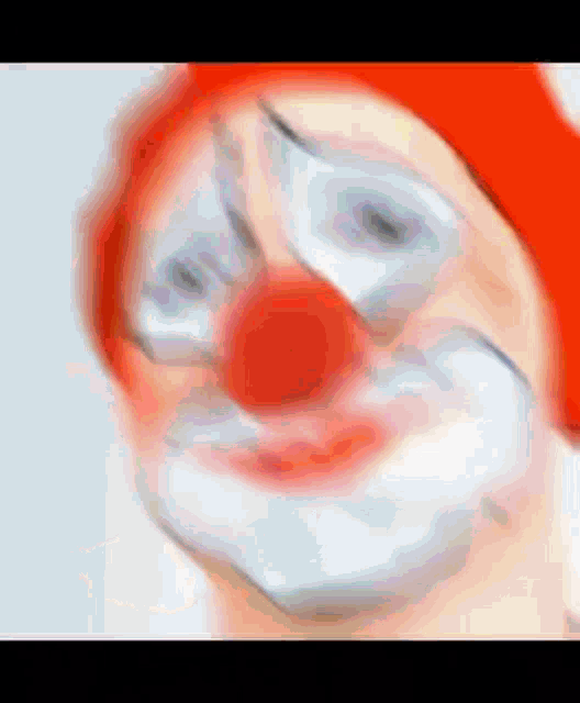 a close up of a clown with a red hat and white face paint