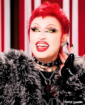a woman with red hair is wearing a fur coat and a choker around her neck