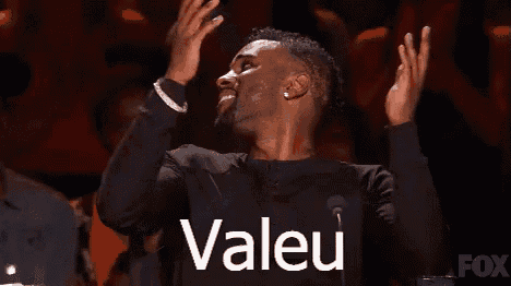 a man is standing in front of a microphone with his hands in the air and the word valeu written on his chest .