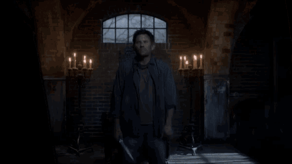 a man stands in front of a brick wall with candles