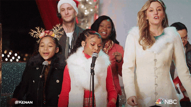a group of people singing into microphones with the nbc logo on the bottom