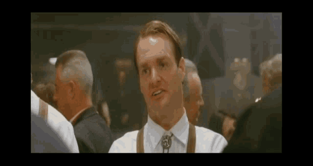 a man wearing a white shirt and brown tie is standing in a crowd of people .