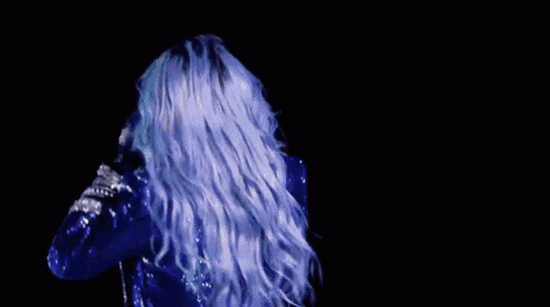 a woman in a blue and black jacket is dancing on a stage in front of a crowd .