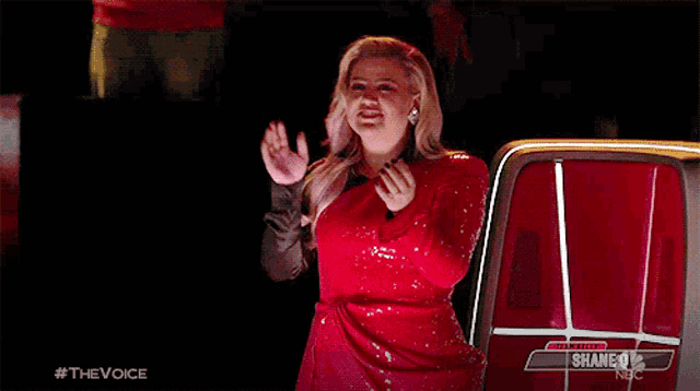 a woman in a red dress is standing in front of a red truck and waving