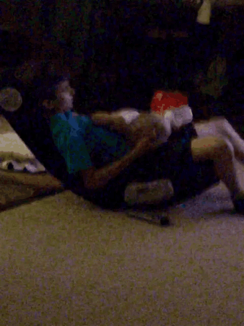 a man in a blue shirt is laying on a couch with his legs crossed