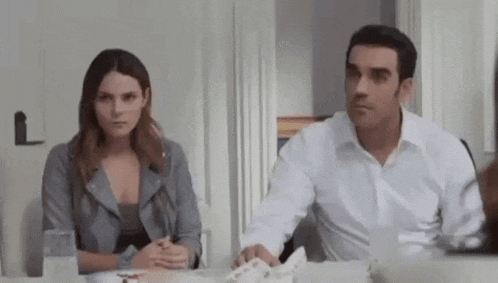 a man and a woman are sitting at a table in a living room .