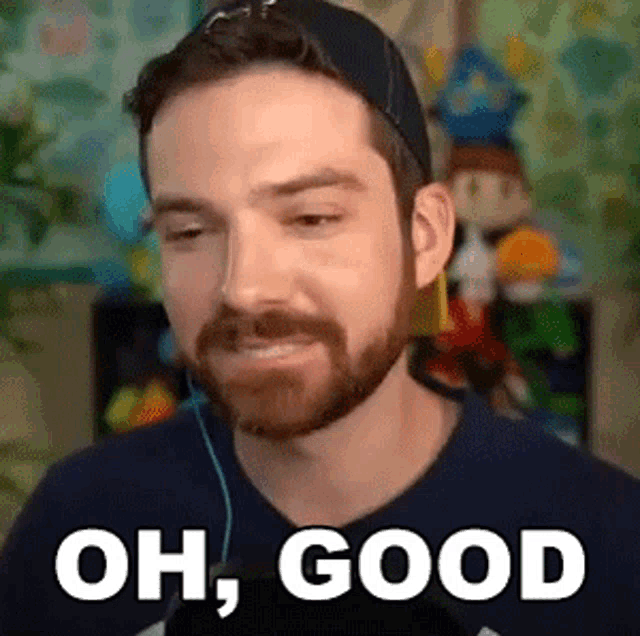 a man with a beard is wearing a hat and headphones and says `` oh , good ''