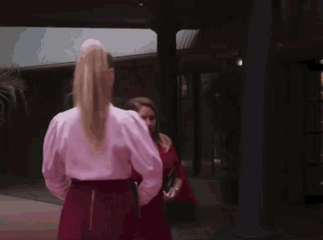 a woman in a pink shirt is standing next to another woman