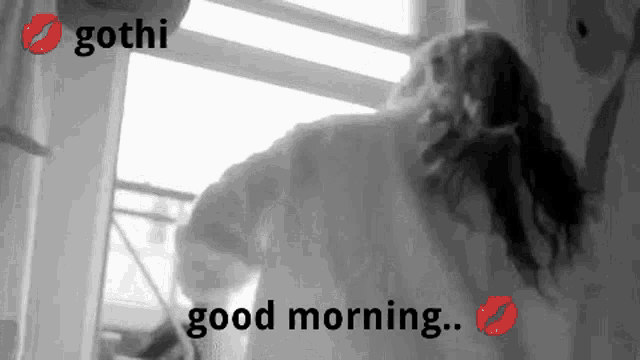 a black and white photo of a woman standing in front of a window with the words good morning written on it .