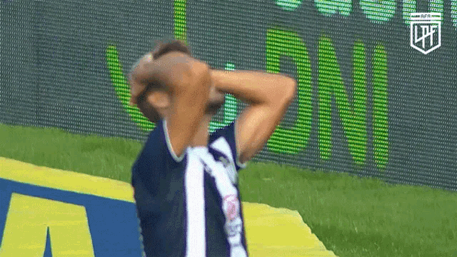 a man in a soccer uniform is standing on a field with his hands on his head .