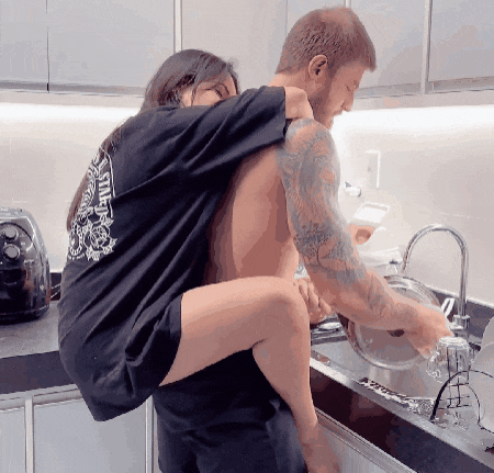 a woman is sitting on a man 's shoulders in a kitchen wearing a shirt that says " italy "