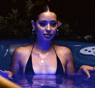 a woman is sitting in a hot tub wearing a bikini top .