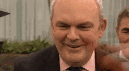 a man in a suit and tie has blood on his face and is smiling .