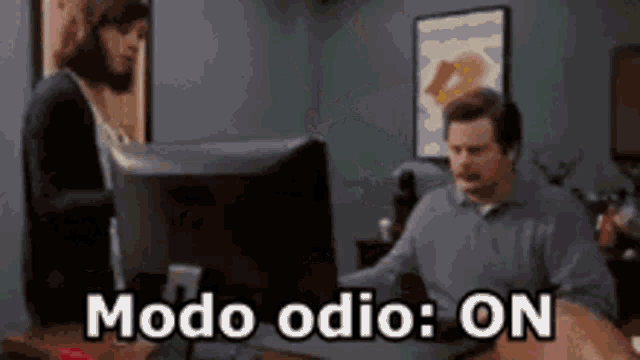 a man is sitting at a desk in front of a computer and says modo odio on .
