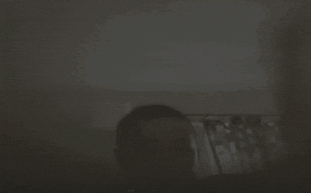 a person is standing in a dark room with a curtain behind them .