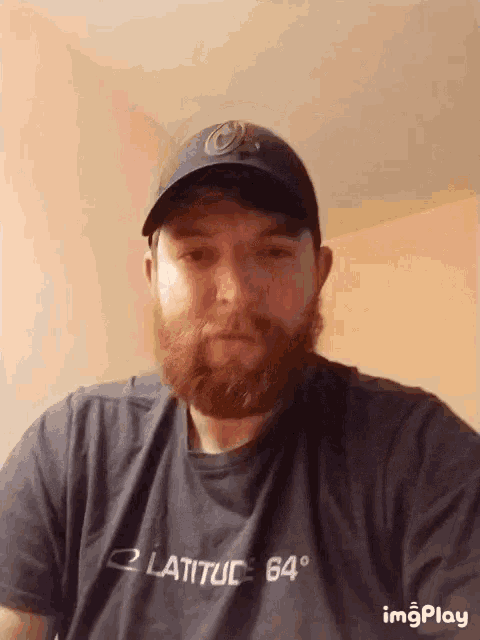 a man with a beard wears a latitude 64 degrees shirt