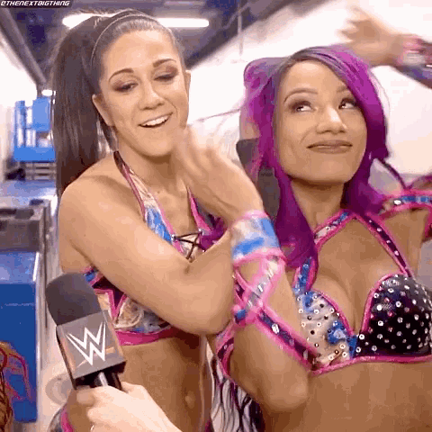 two women with purple hair are standing next to each other and one has a microphone in her hand