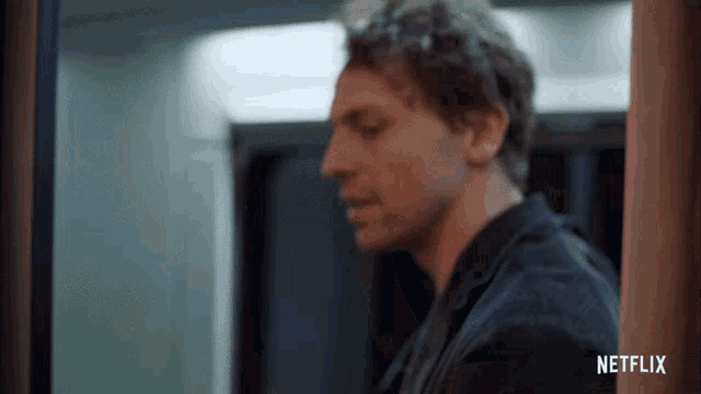 a man is standing in a hallway with a netflix logo on the bottom