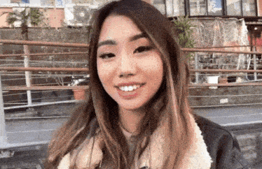 a young woman wearing a fur coat and a leather jacket is smiling .