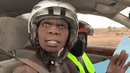 a man wearing a helmet and a yellow vest is in a car