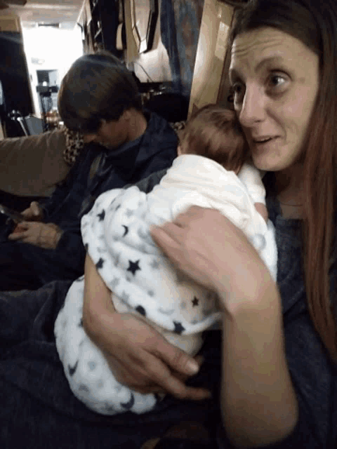 a woman is holding a baby wrapped in a star blanket