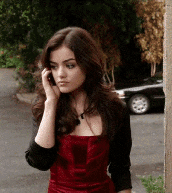 a woman in a red dress is talking on her phone