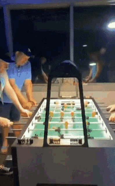 a group of people are playing a game of foosball in a room