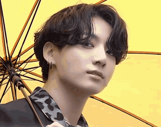a young man is holding a yellow umbrella