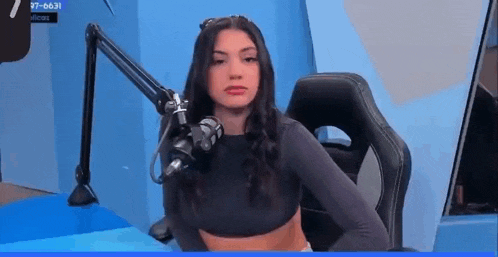 a woman in a crop top is sitting in front of a microphone .