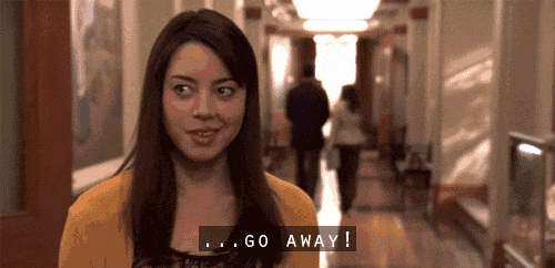 a woman in a yellow sweater says go away in a hallway