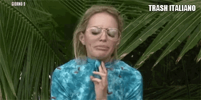 a woman wearing glasses and a blue shirt is making a funny face .