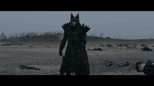 a man in a black costume with horns is standing in a field