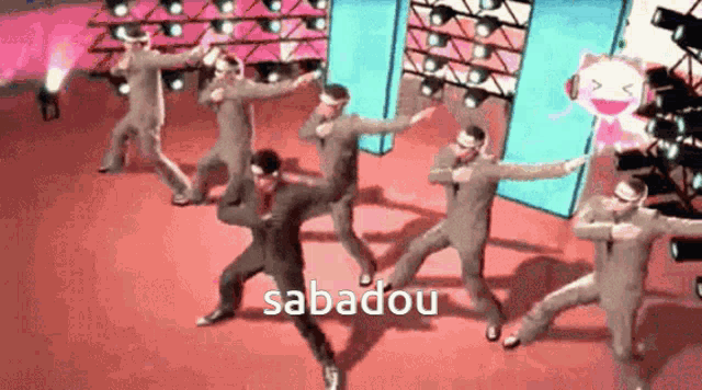 a group of men are dancing on a stage and the word sabadou is on the bottom of the screen .