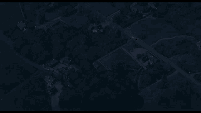 an aerial view of a residential area at night with houses and trees